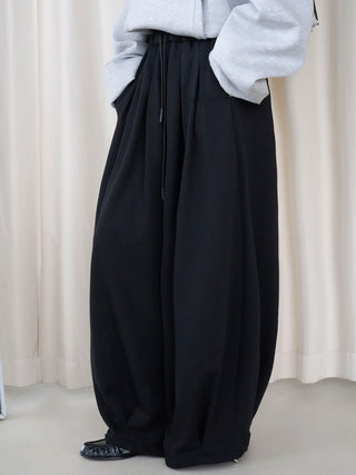 Black drawstring balloon pants with voluminous legs, front angled view
