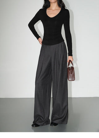 Close-up of charcoal pinstripe trousers showing pleated front and wide legs