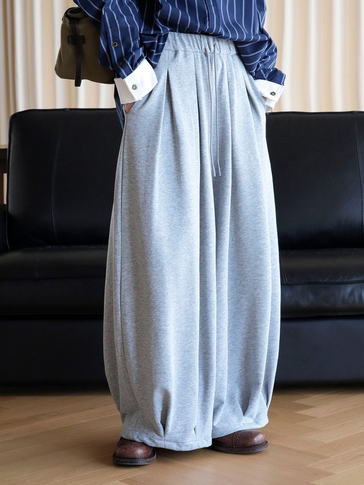 Grey balloon pants showing front pleats, elastic waist and relaxed hems