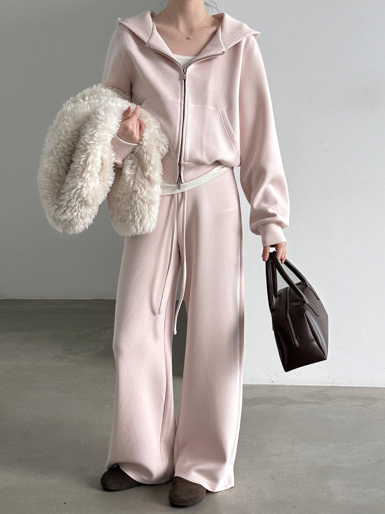 Pale pink hoodie showing relaxed sleeves and front pocket details