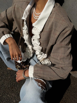 Front view of a model wearing a plaid ruffle trim zip jacket with white cuffs