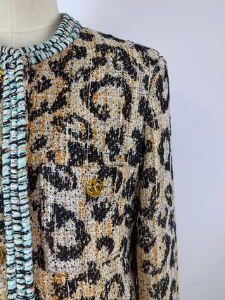 Close-up of leopard fabric texture, pale blue braided neckline and gold-tone button