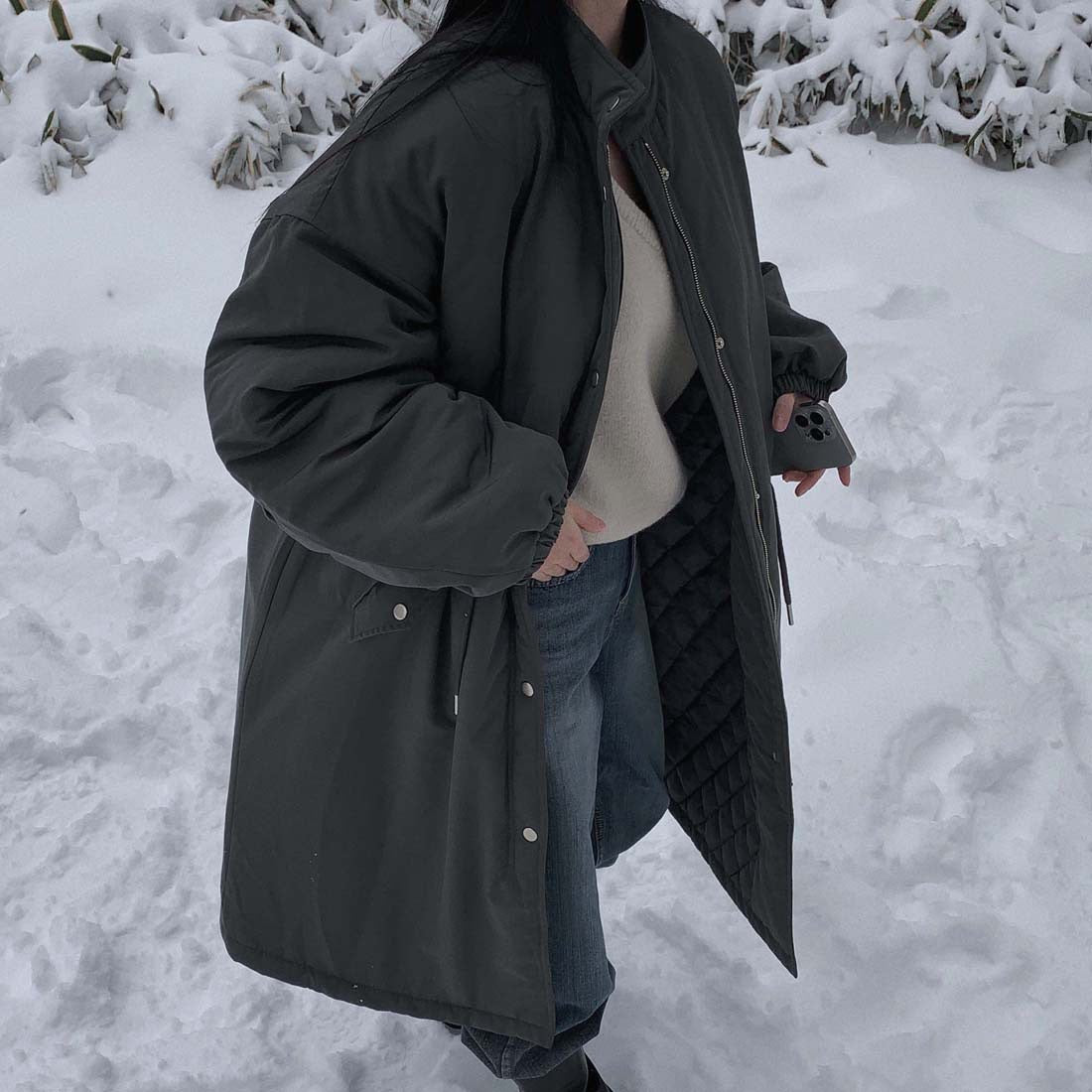 Black parka showing front zip, snap placket and quilted lining